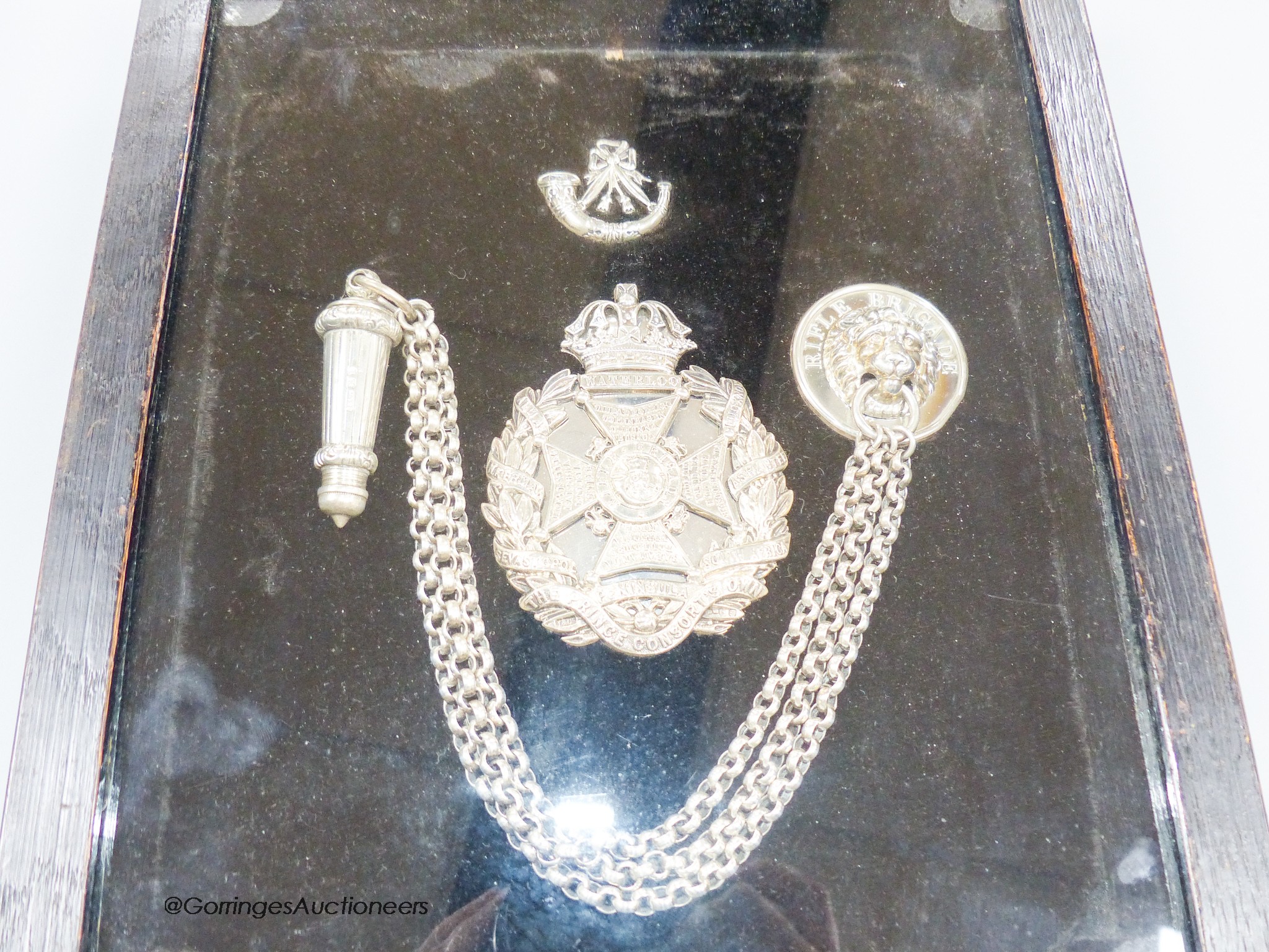 A framed late Victorian silver Rifle Brigade whistle and belt chain and two silver badges